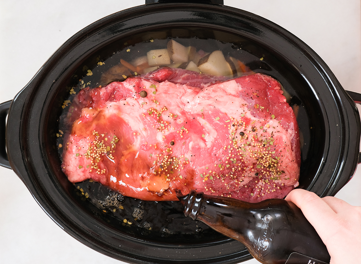 adding stout to a slow cooker with seasoned corned beef