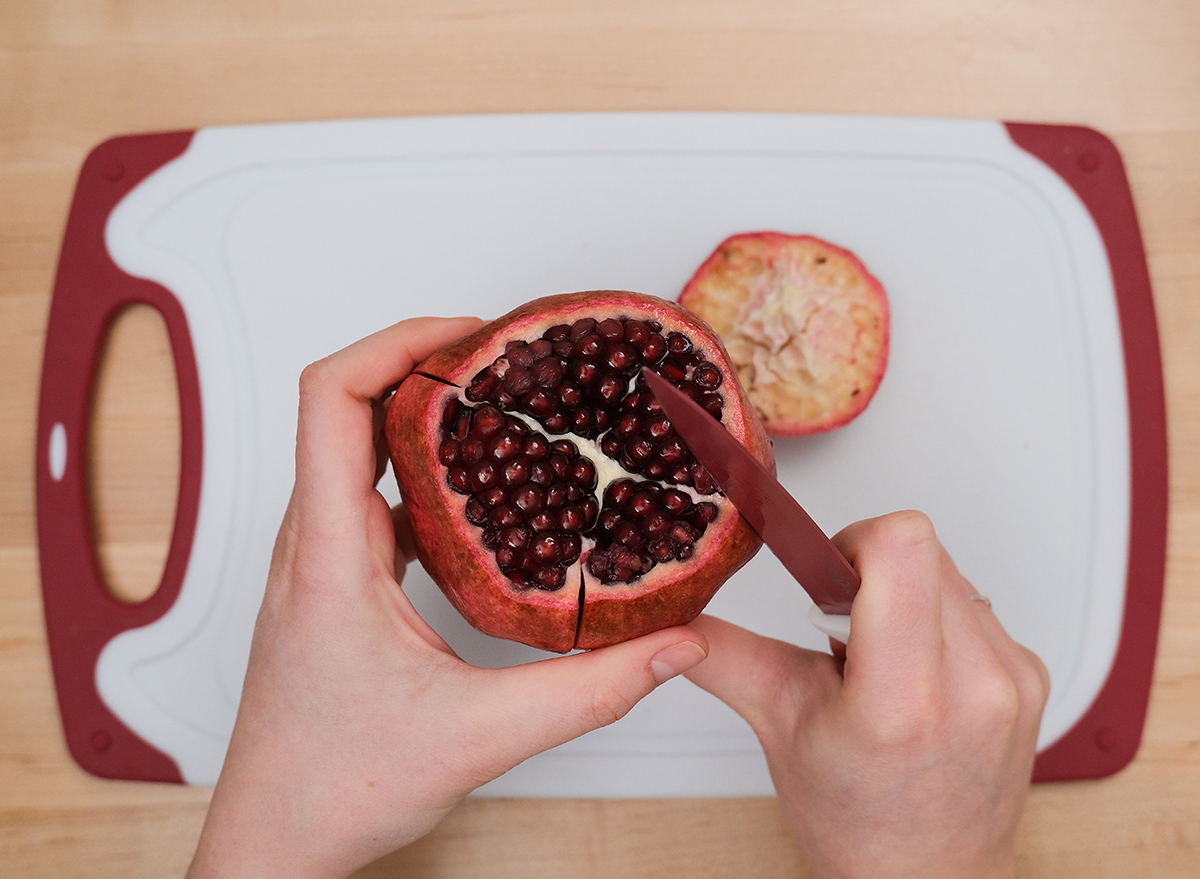 cutting into the side of a pomegranate