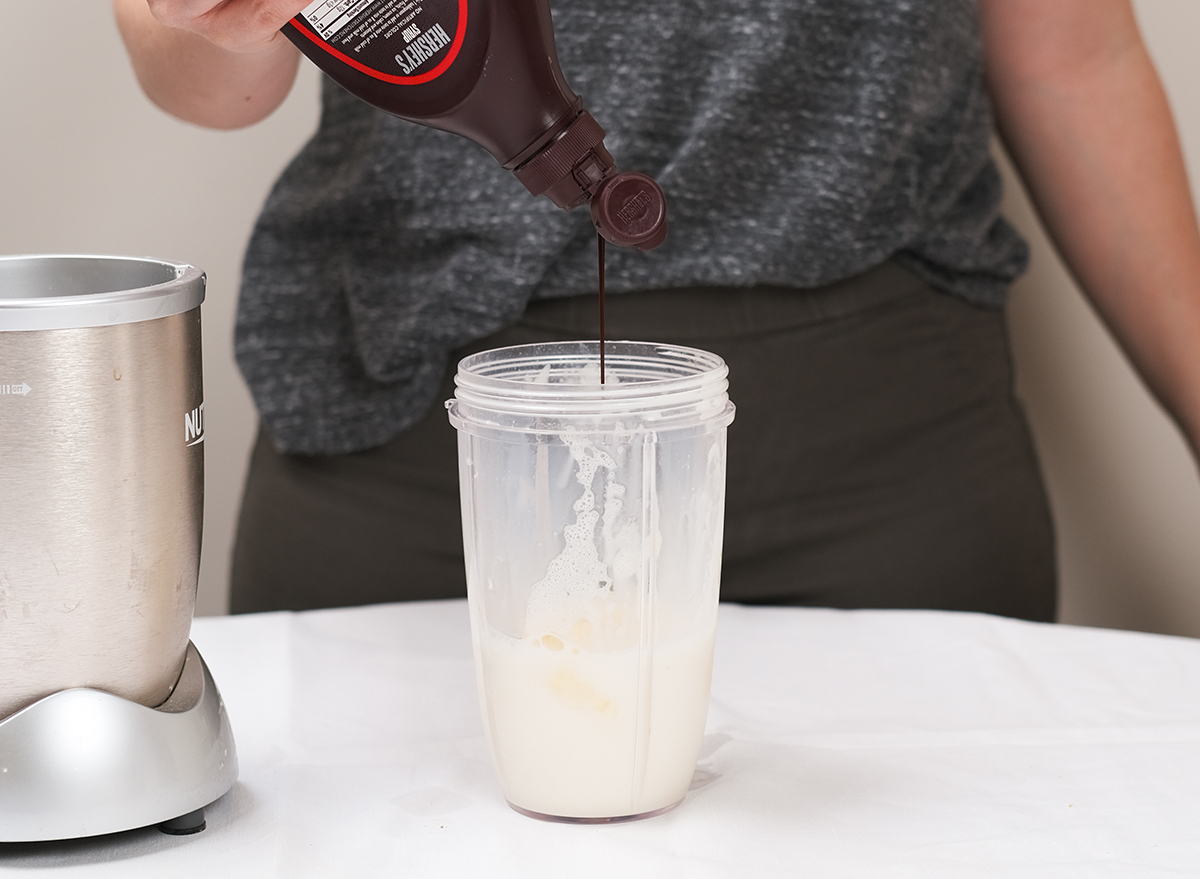 adding chocolate sauce to a blender with milkshake mixture