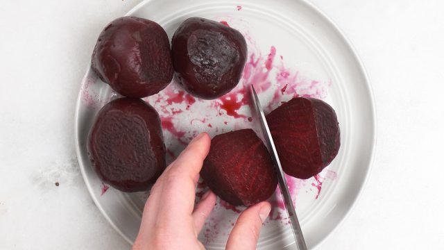 slicing open roasted beets on a plate
