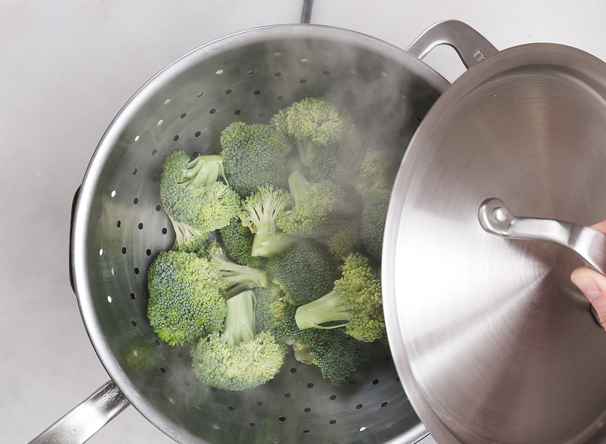 covering broccoli in a colander for steaming
