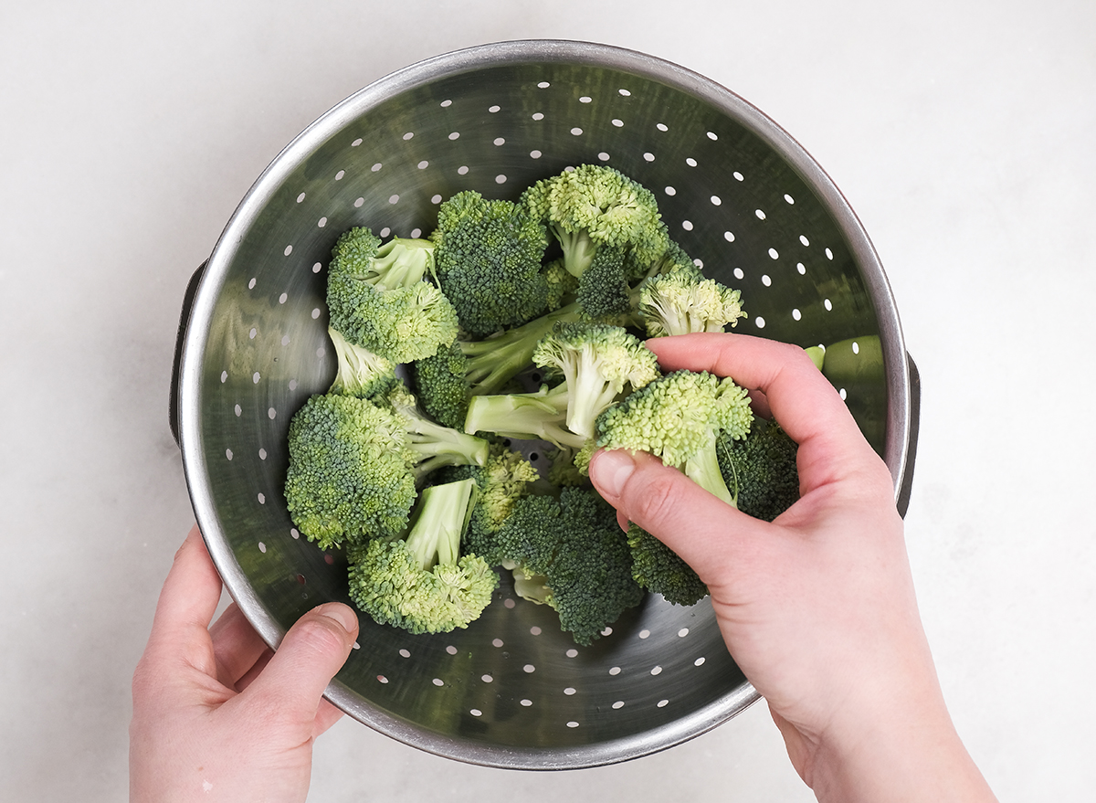 placing broccoli in a colander to steam