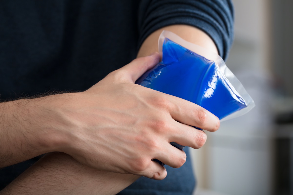 Person Applying Ice Gel Pack On An Injured Elbow At Home