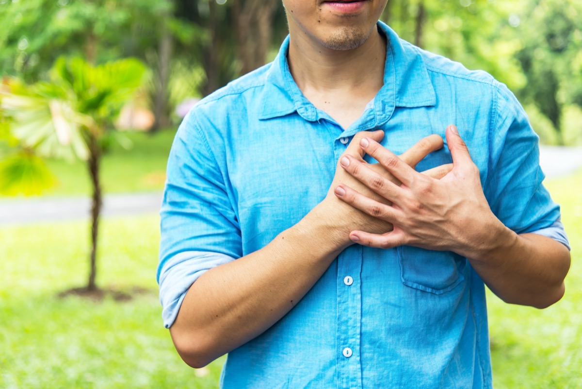 man holding hands on chest suffering from heart attack