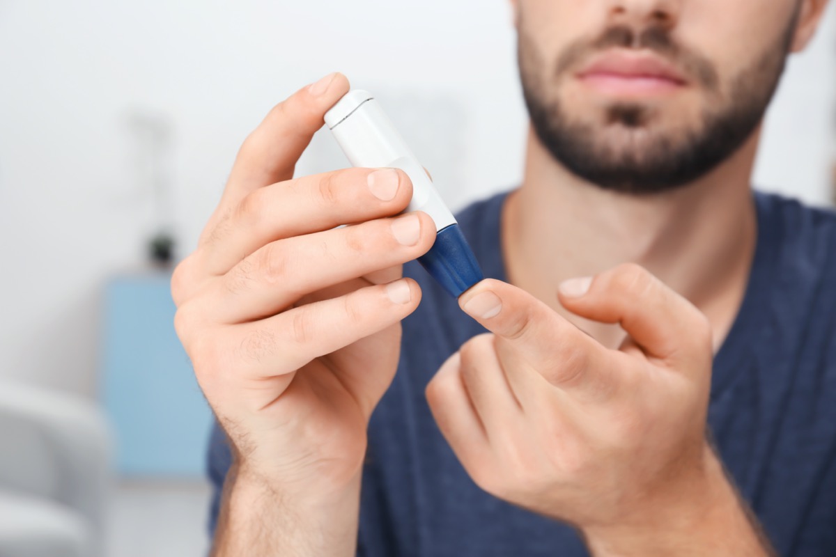 Man taking blood sample with lancet pen indoors