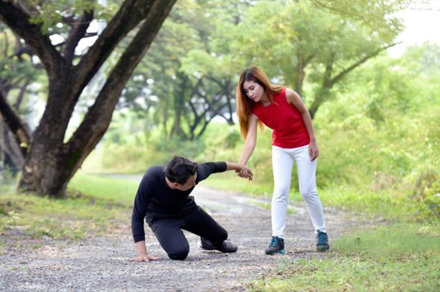 Woman helping injured man on running track in garden