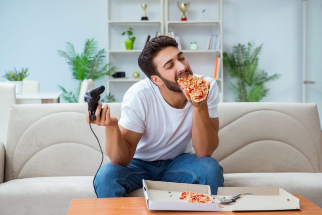 Mężczyzna je pizzę na wynos w domu relaksujący odpoczynek