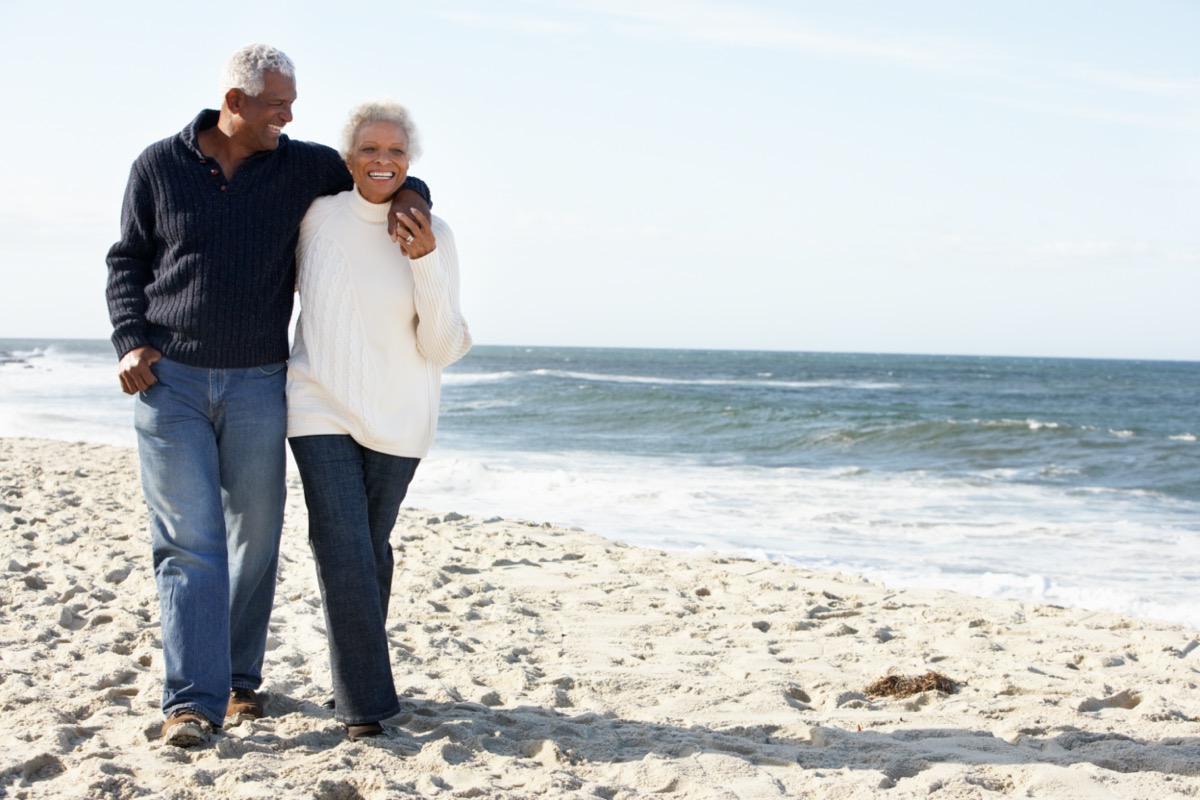 Senior Couple Walking Along Beach Together