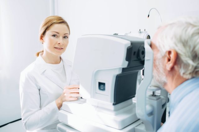 Asian senior woman sitting at optometrist's office while doctor wearing optometrist trial frame on her face to check her eyesight
