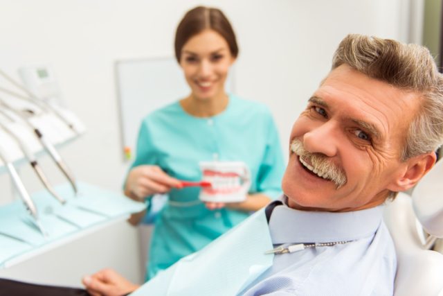 Elderly man on a review of a dentist, sitting in a chair.