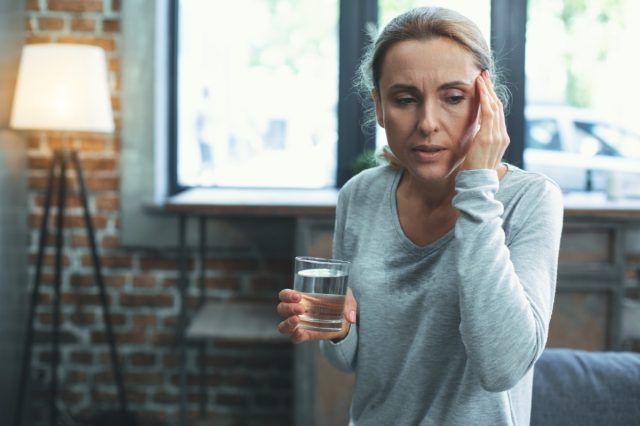 Shortness of breath. Unhappy mature woman sweating and touching head