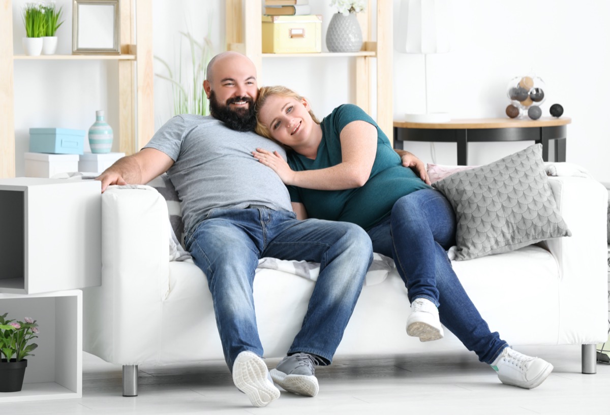 Overweight couple watching tv at home