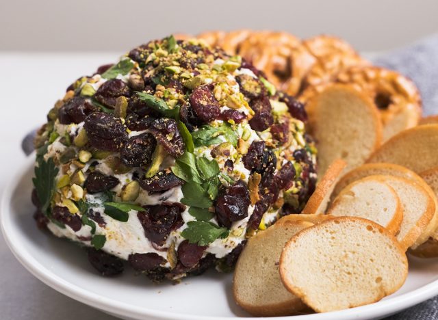 pistachio cranberry cheese ball with snacks on a plate