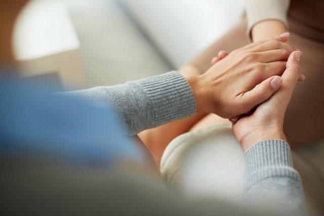 Close up of a psychiatrist's hands holding his patient's palm