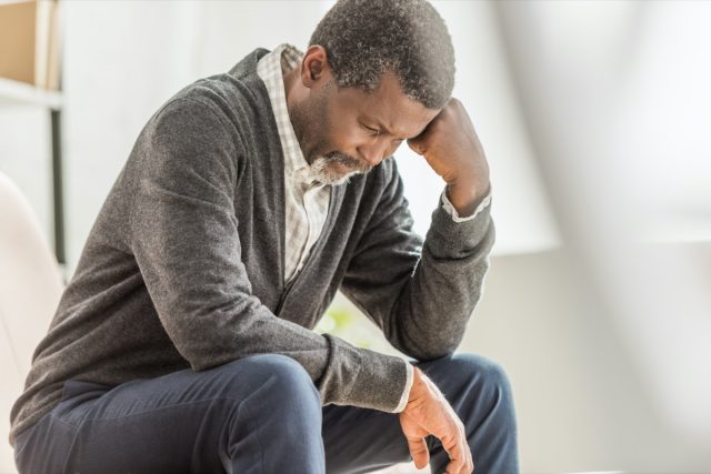 selective focus of depressed african american man sitting with head down
