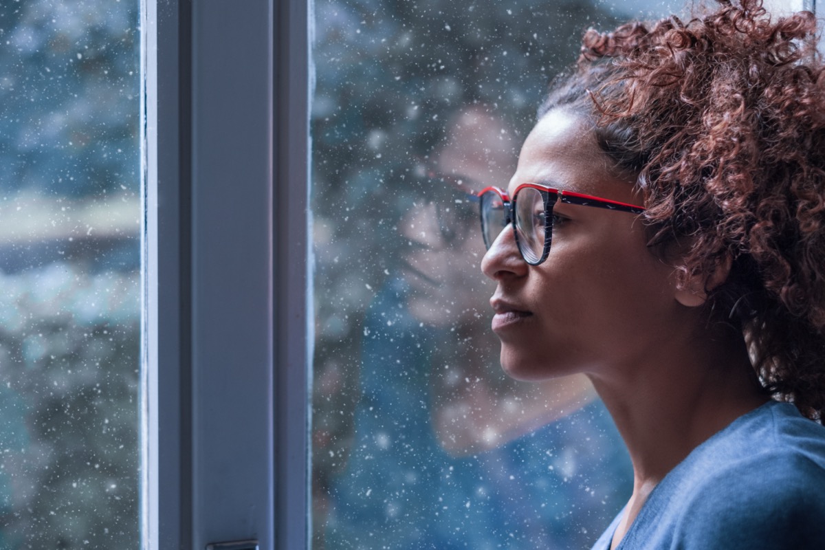 Donna triste che guarda fuori dalla finestra