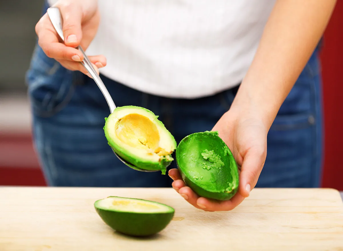 woman scooping out avocado with spoon