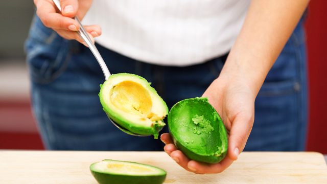 woman scooping out avocado with spoon