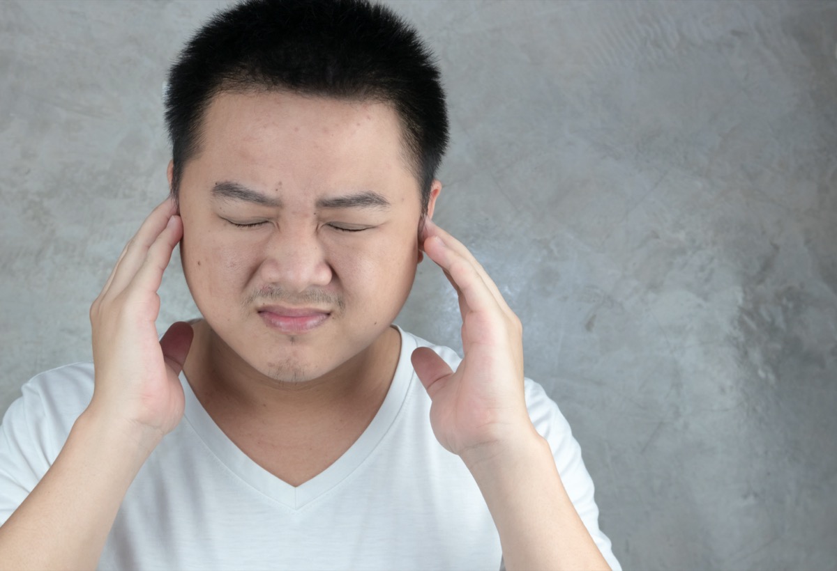 Asian men use hands to close their ears.