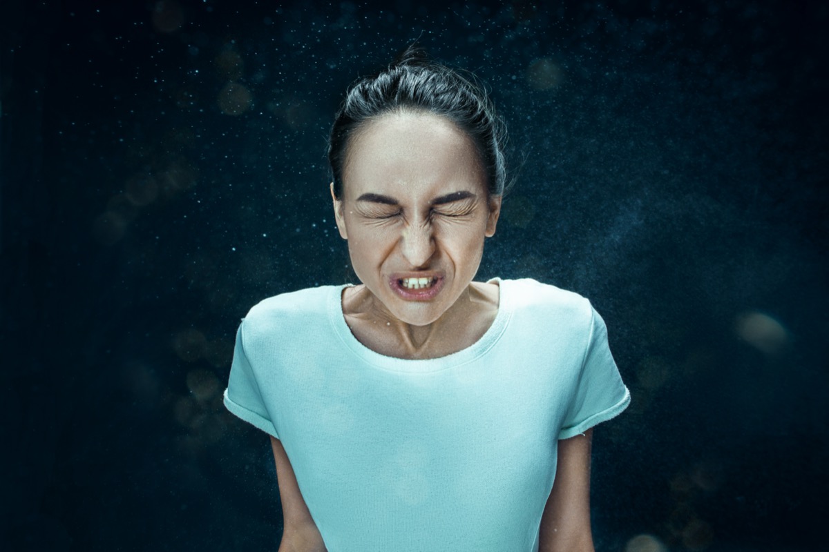 woman sneezing with spray and small drops
