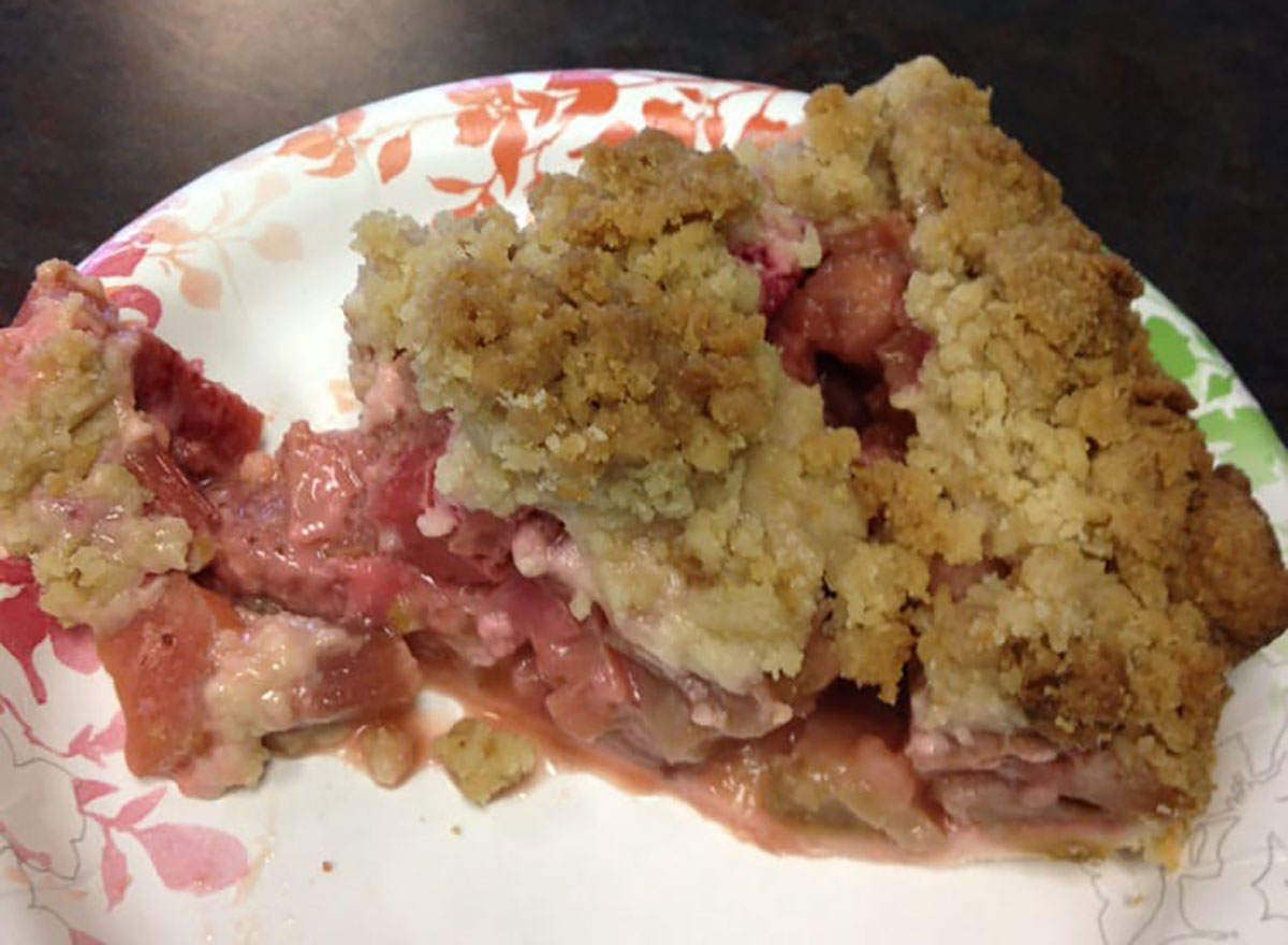 strawberry rhubarb pie slice on paper plate with crumb topping