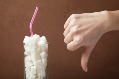 Sugar cubes in glass and hand shows thumbs down.