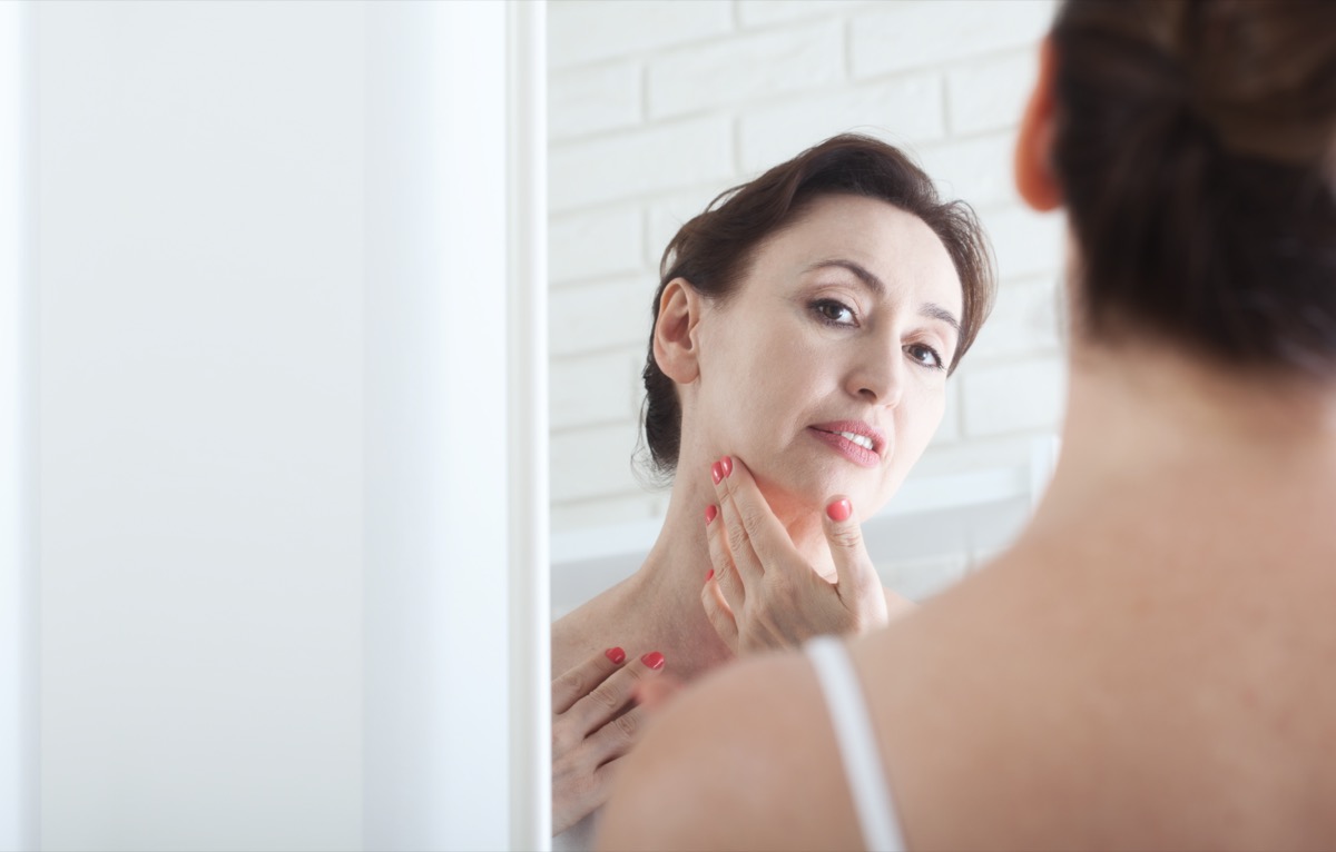 Woman checking face mirror spots moles