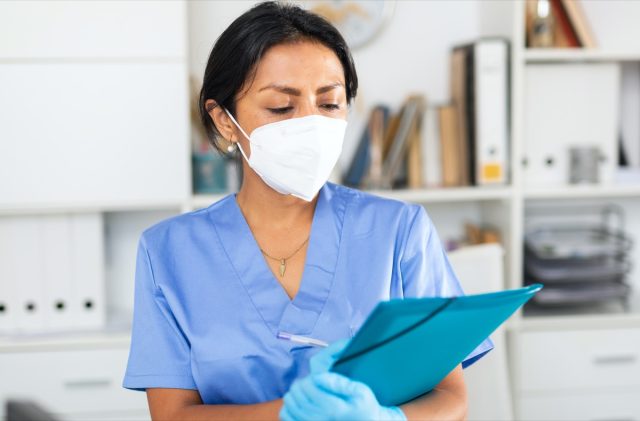 female doctor in surgical face mask meeting patient in medical office