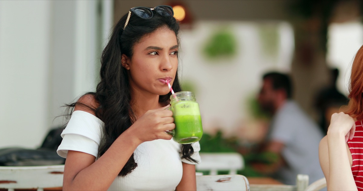 Woman drinking healthy green juice outdoors