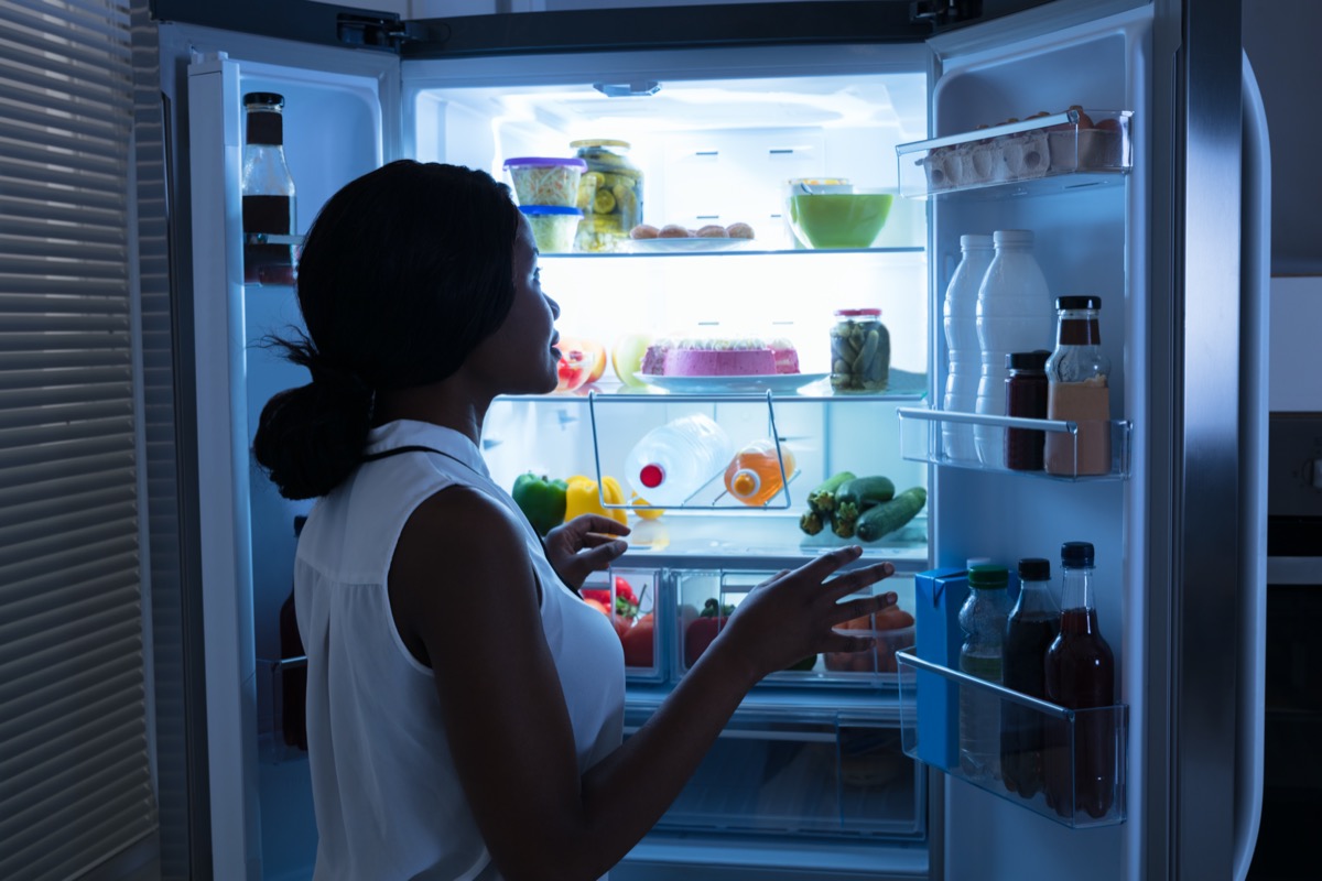 Woman Taking Out Bottle From Open Refrigerator