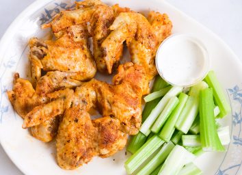finished chicken wings with blue cheese dip and celery on a plate