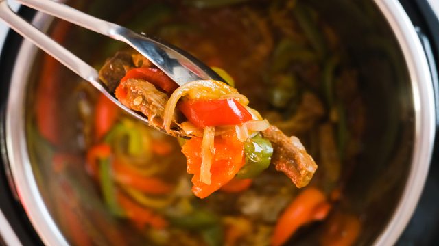 holding steak fajita filling with tongs from an Instant Pot