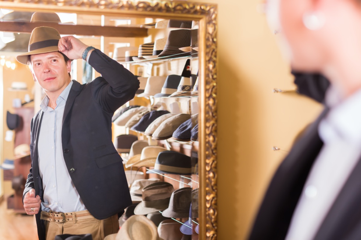 customer try on brim hat and looking in mirror at dressing room