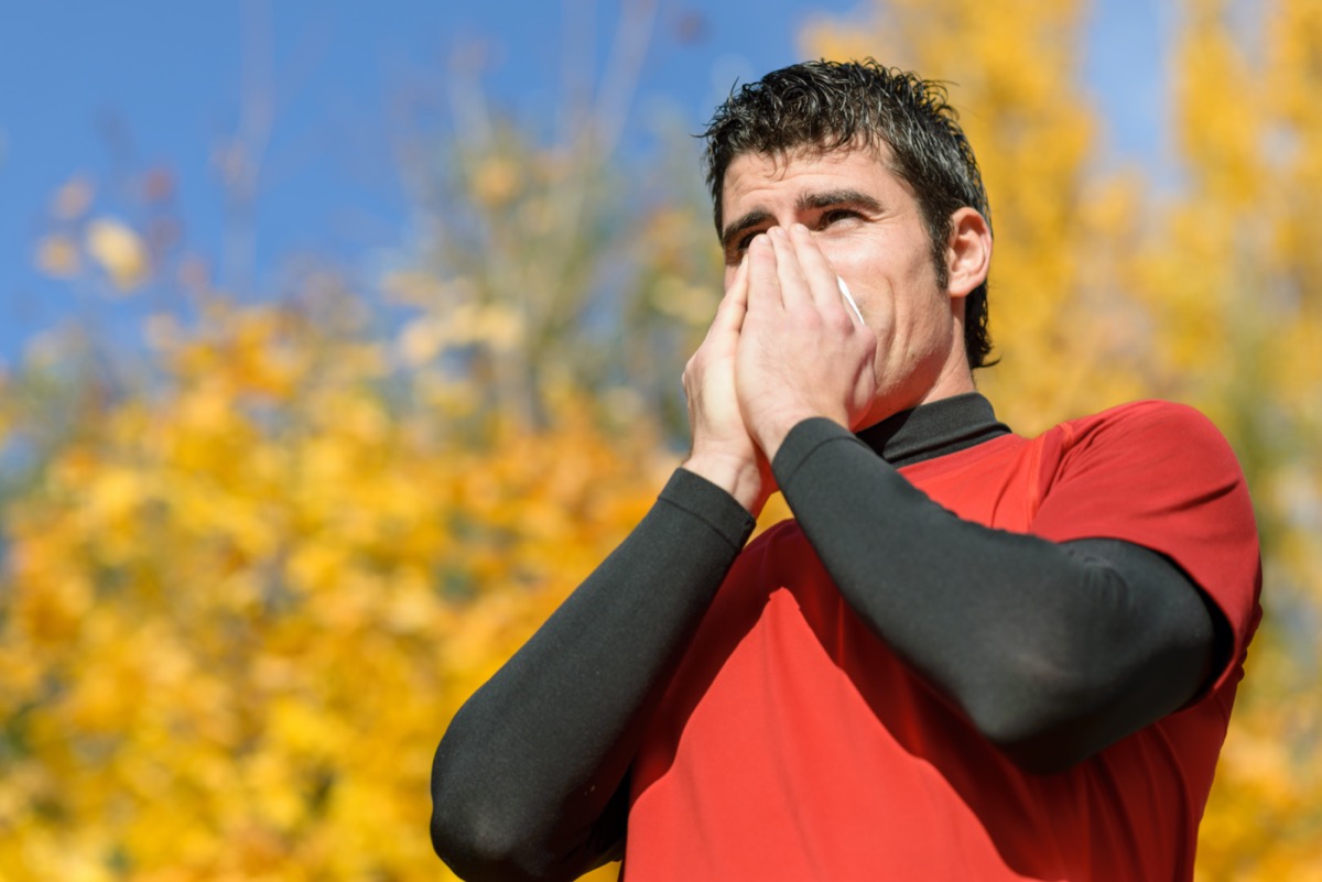 Flu and cold man. Young athlete coughing and blowing on a tissue. Caucasian