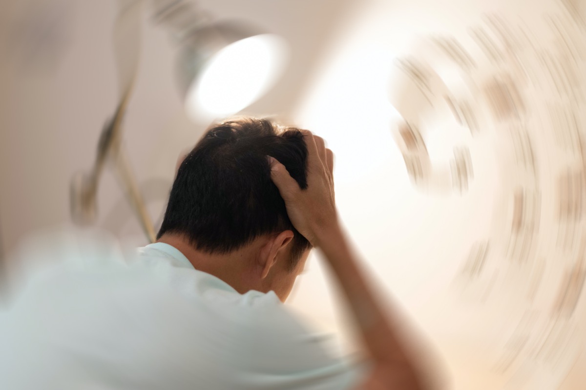 Man hands on his head felling headache dizzy sense of spinning dizziness,a problem with the inner ear, brain, or sensory nerve pathway