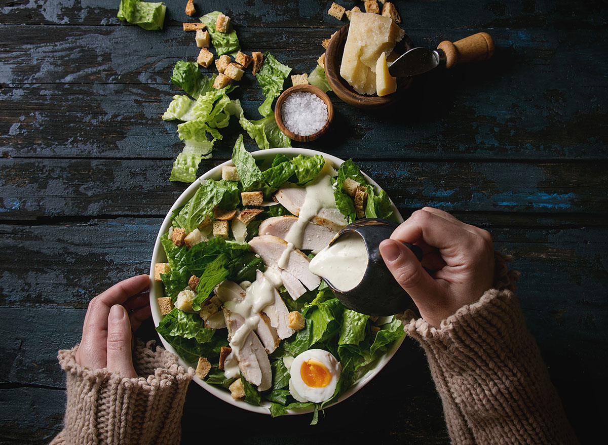 Women pouring dressing on salad