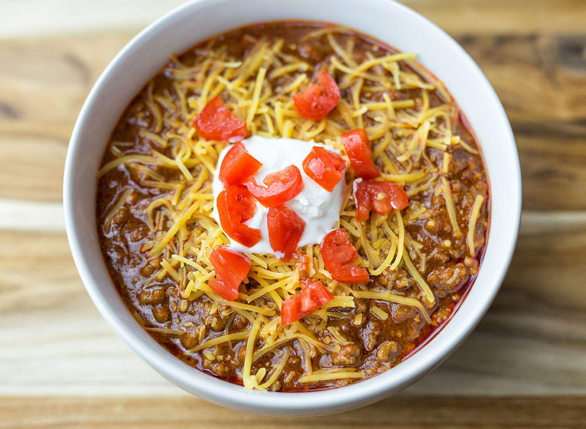 bowl of texas chili topped with cheddar cheese and tomato