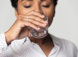 with closed eyes drinking clean mineral water close up, young woman holding glass