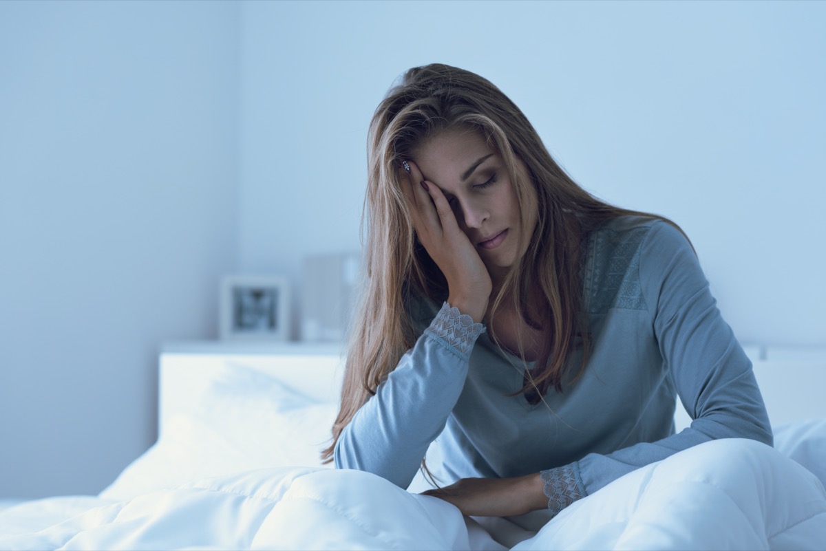 Depressed woman awake in the night, she is touching her forehead and suffering from insomnia