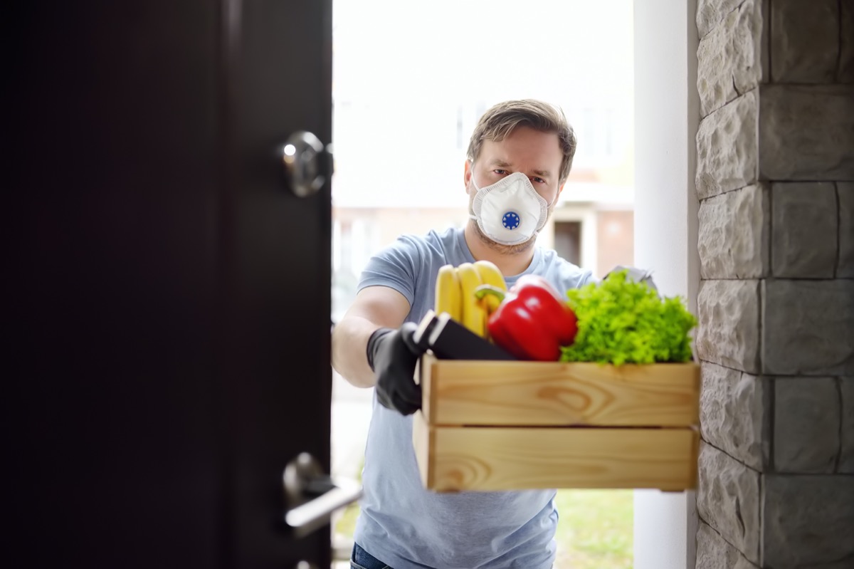 volunteer delivering shopping during coronavirus quarantine. Customer receiving online order from courier at home