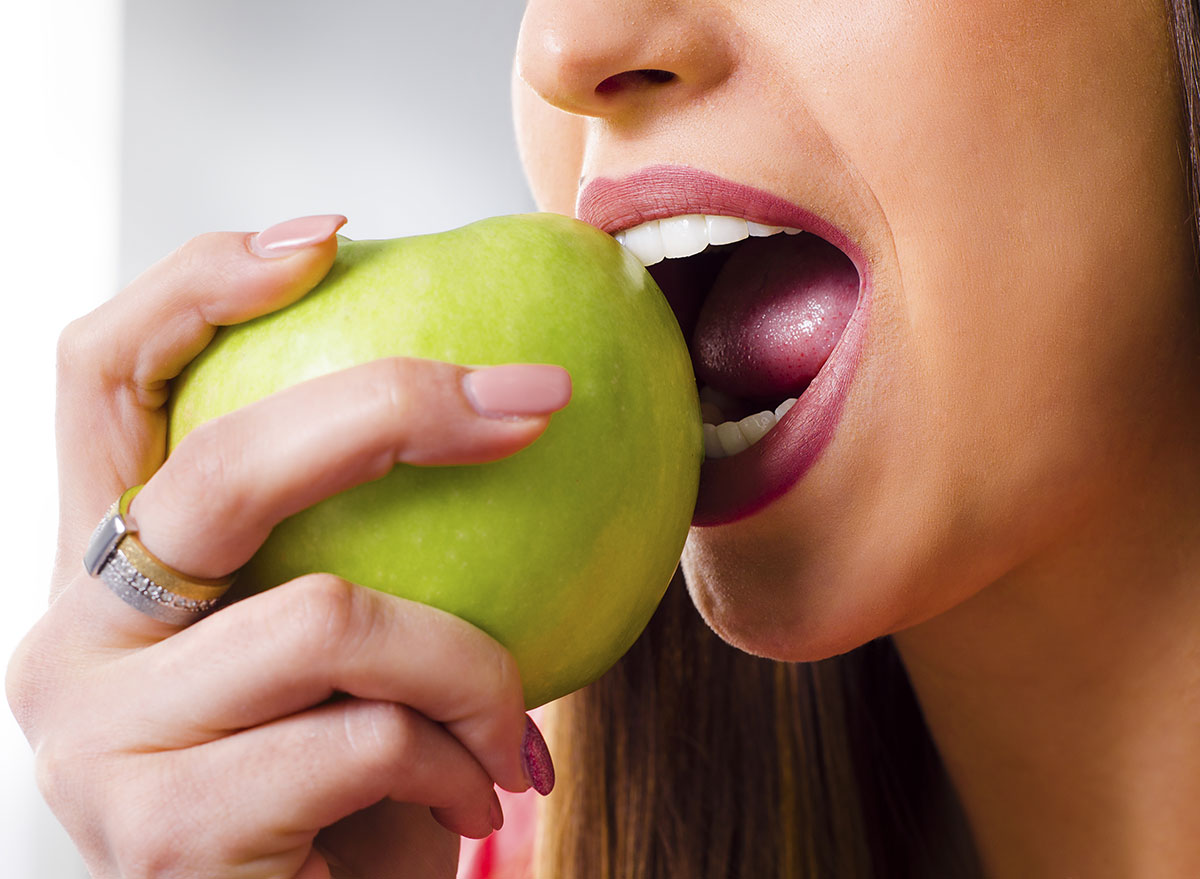 woman biting into apple with teeth