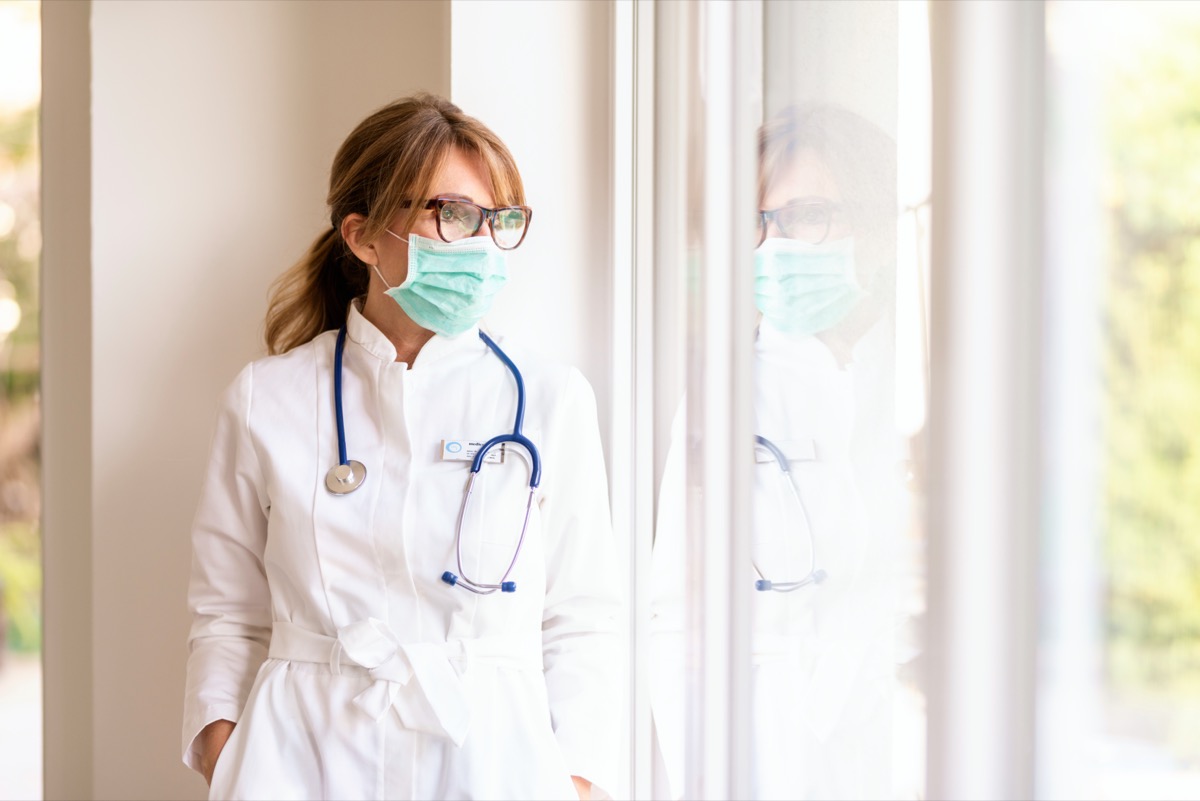 female doctor wearing face mask for prevention while standing by the window and looking out.