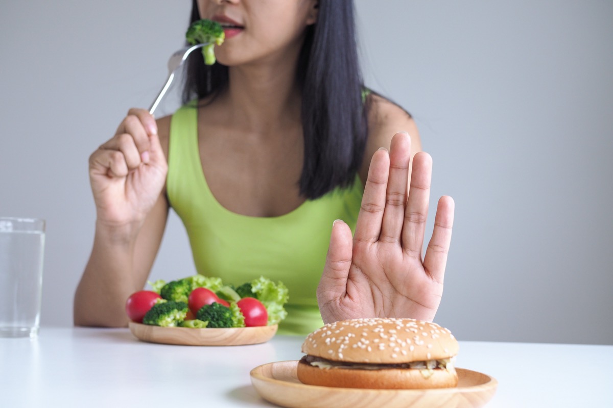 Woman eat salad no hamburger hand unhealthy food