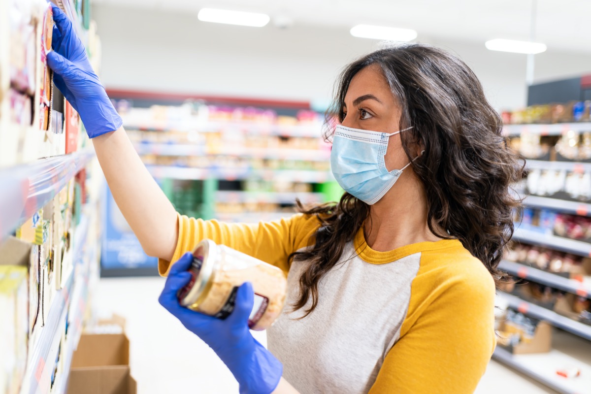 Royalty-free stock photo ID: 1737876836 Young woman with mask and gloves comparing various fresh pasta essentials at the supermarket in the fresh produce section