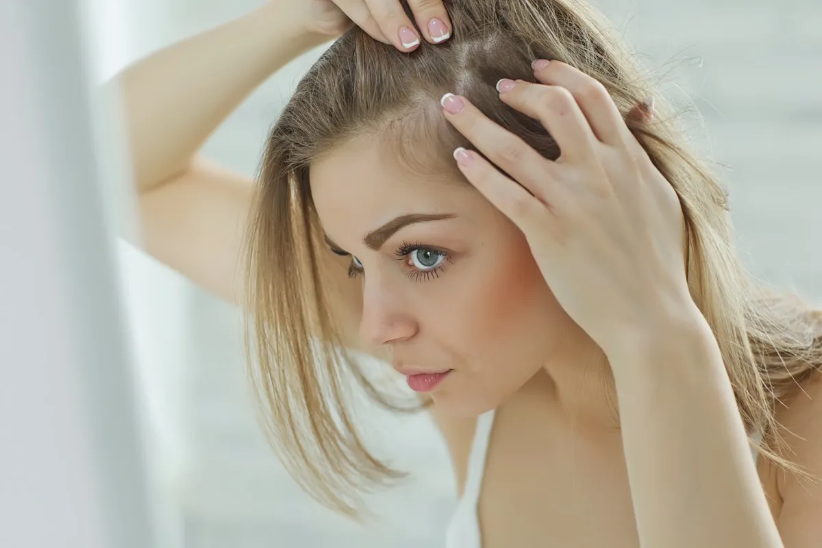 nervous girl looking in the mirror her scalp