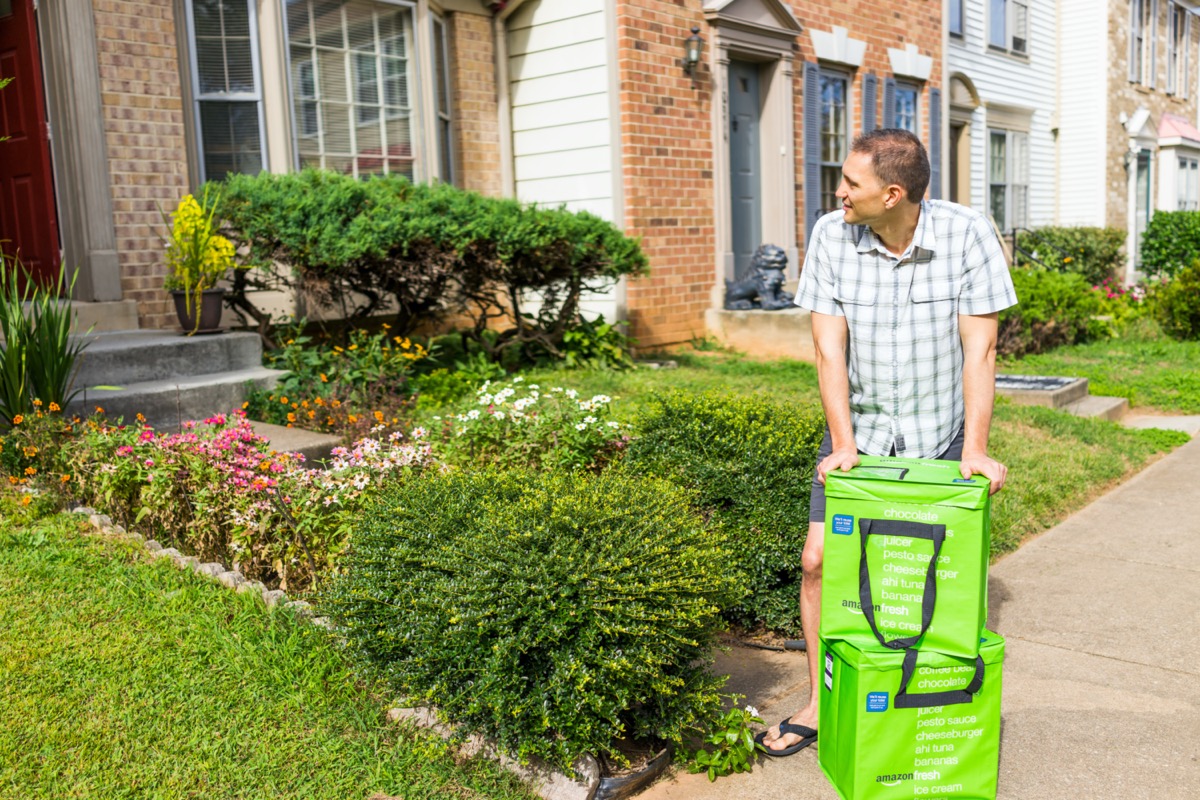 Amazon Fresh insulated grocery delivery bags, totes on front home house porch closeup with young man picking them up