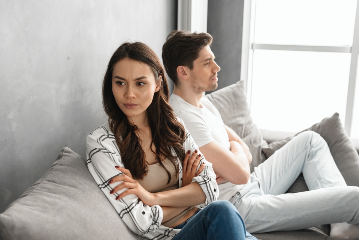 resentful guy and girl acting like arguing couple and not speaking to each other, while sitting together on couch at home