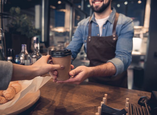 Customer handing coffee cup to barista