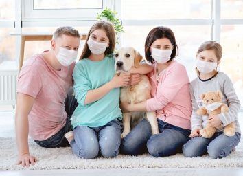 Beautiful family in medical masks against coronavirus at home