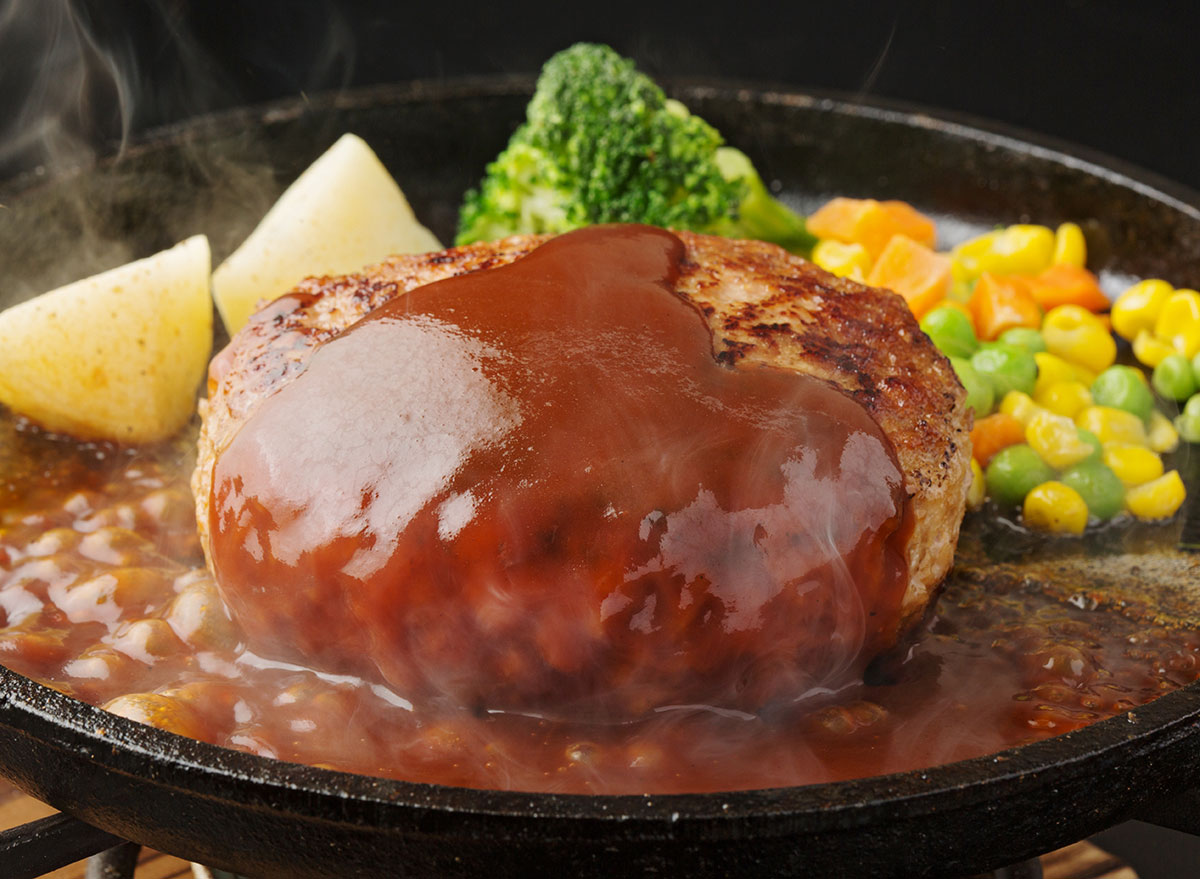hamburg steak with frozen vegetables and potatoes in brown sauce in skillet